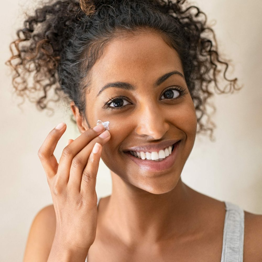 Smiling,African,Girl,With,Applying,Facial,Moisturizer,While,Holding,Jar